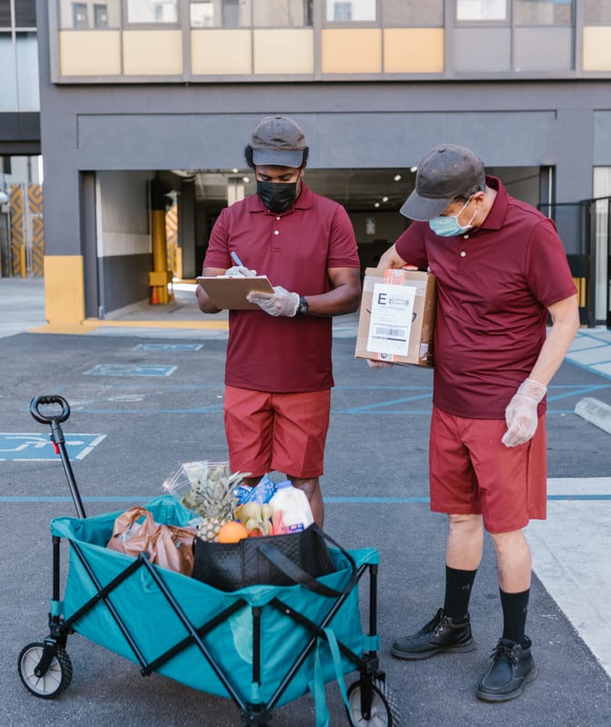 Two couriers checking a parcel against a delivery list